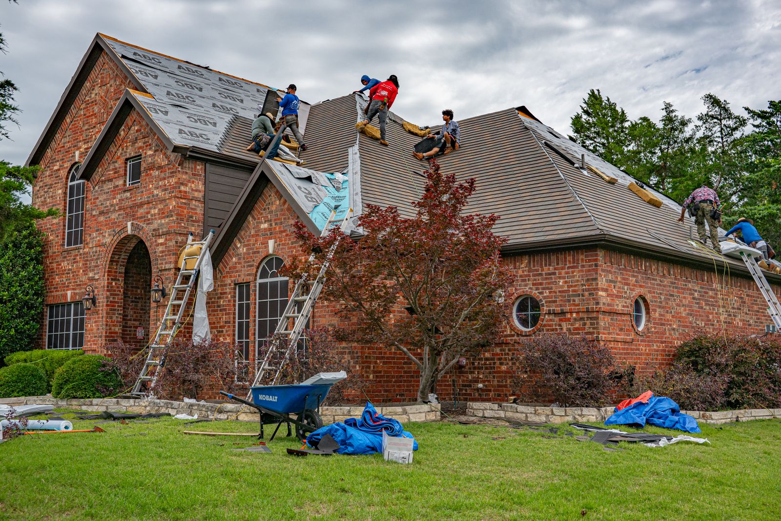 A roofing crew installing a new shingle roof on a brick home